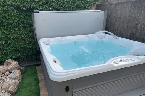 Spa installé dans un jardin, couvercle relevé