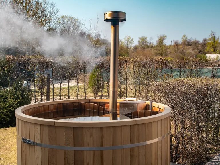 Bain nordique Harvia en bois chauffé par un poêle à bois, vapeur au-dessus de l'eau, dans un jardin