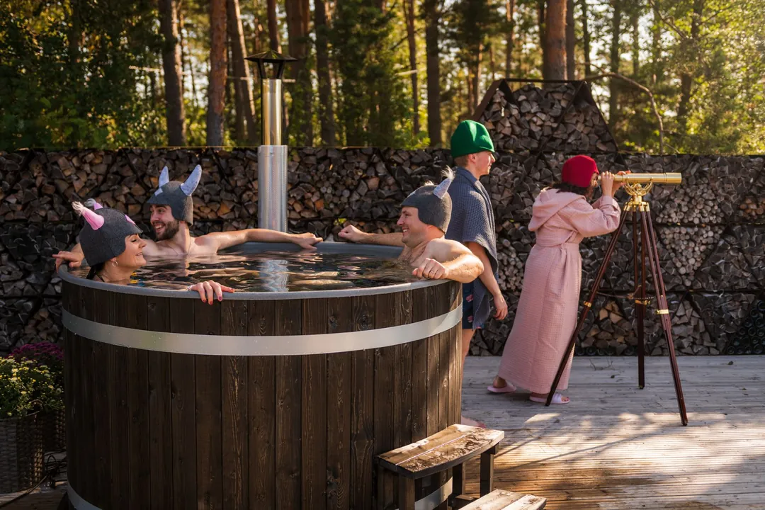 Bain nordique Harvia en épicéa teinté charbon dans un jardin boisé