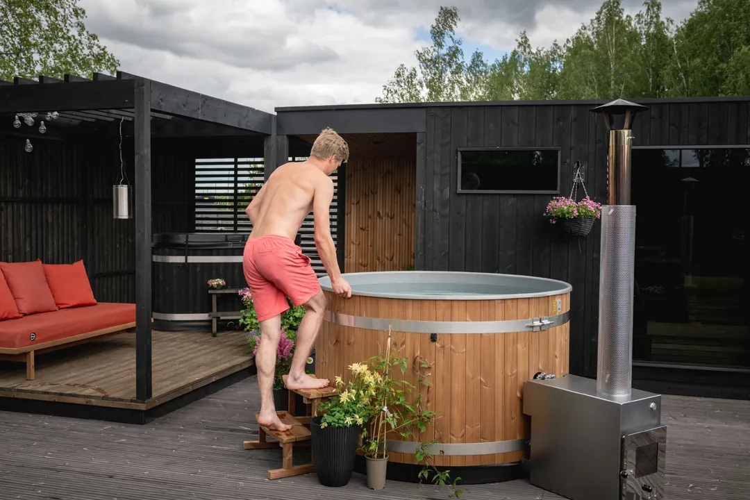 Bain nordique Harvia en pin thermo-traité brun devant un pavillon noir