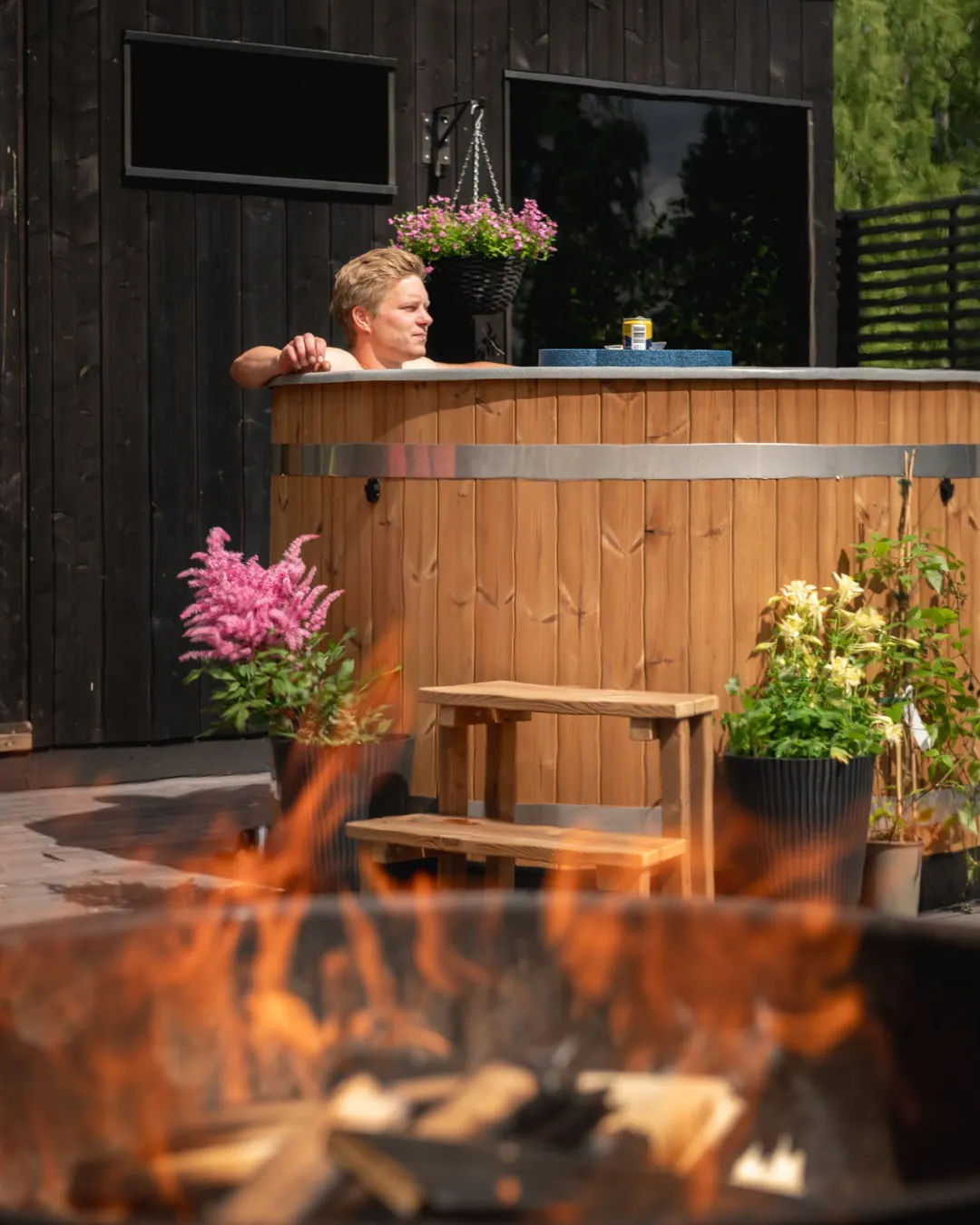 Flammes dans le foyer du poêle à bois extérieur d’un bain nordique Harvia, la cuve en arrière-plan