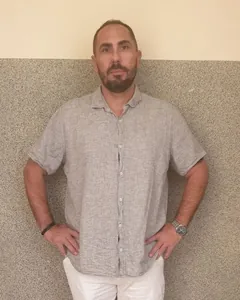 Christophe Salvador, mains sur les hanches, en chemise de lin grise