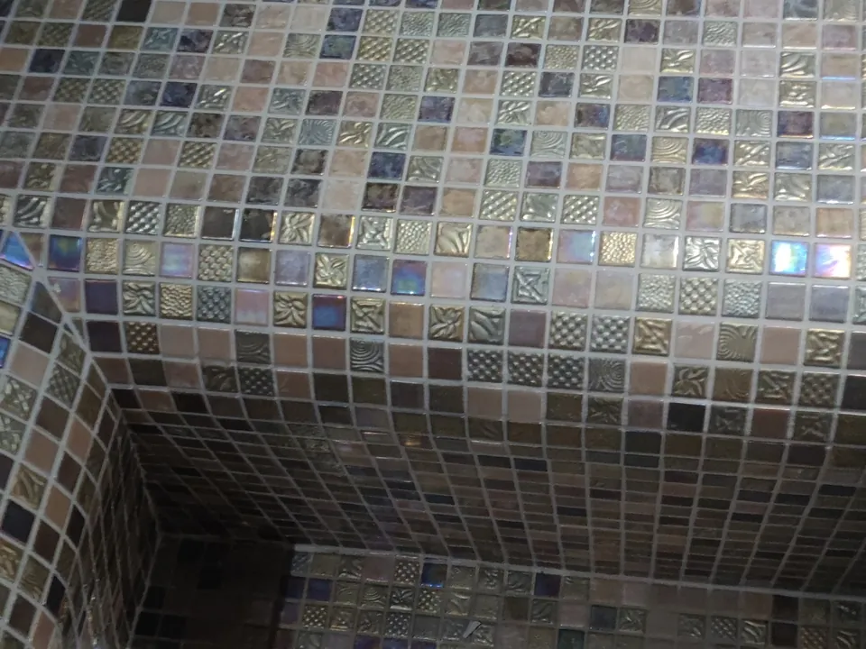 Intérieur d’un hammam carrelé de mosaïque irisée aux reflets bronze et mauves