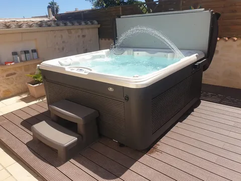 Spa avec jeu d'eau installé sur une terrasse en bois, avec son marchepied