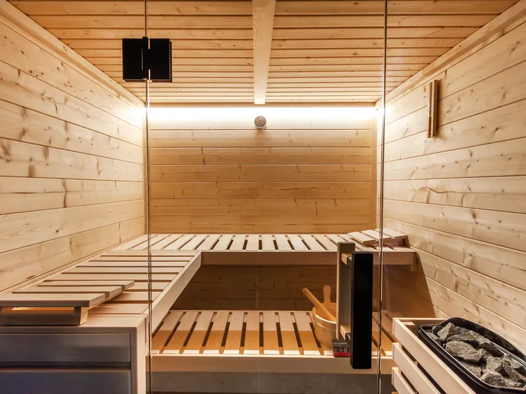Intérieur d'un sauna Harvia Family : bancs en bois clair, poêle et éclairage indirect