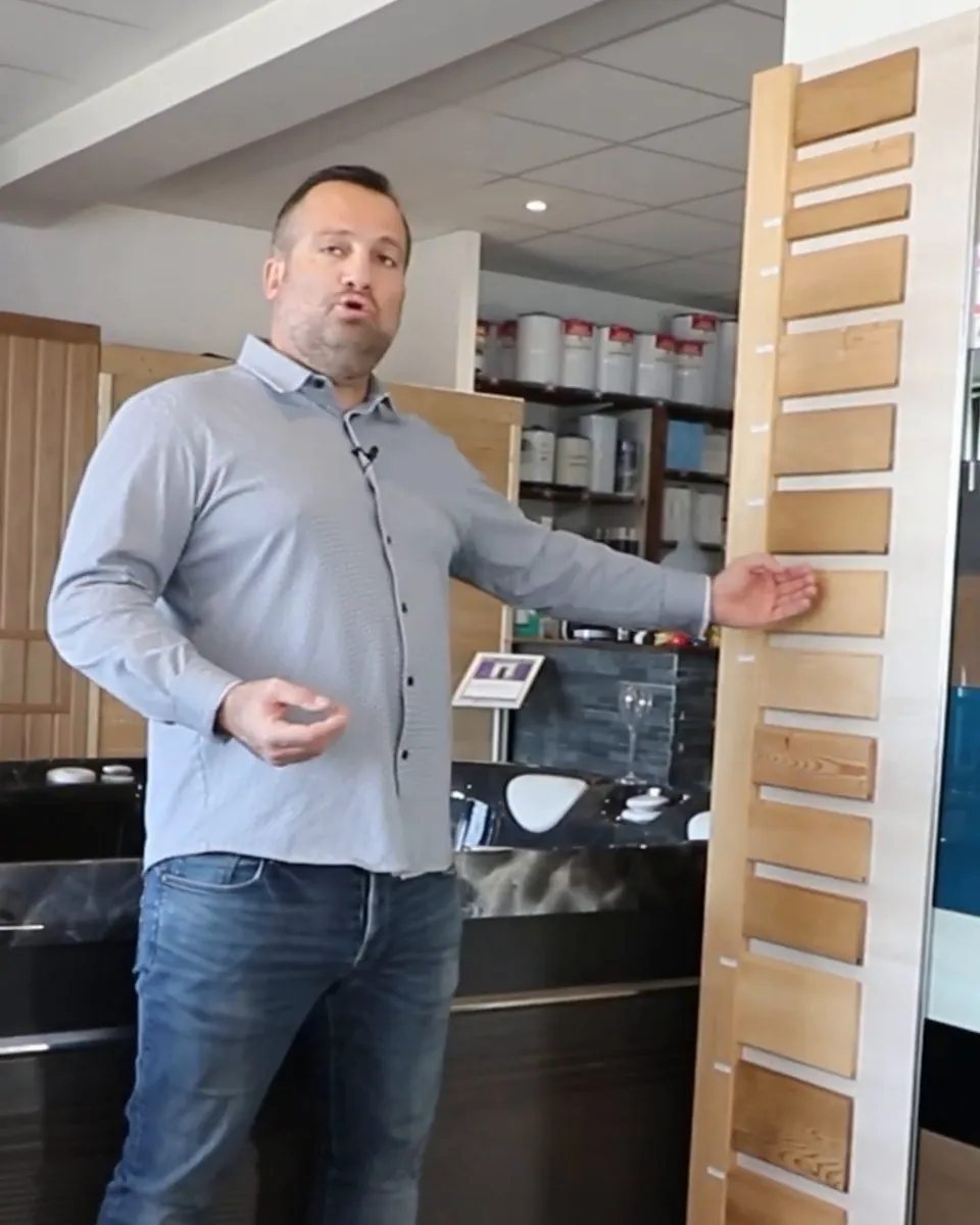 Au showroom Sommum Wellness de Gigean, un conseiller présente un nuancier de bois